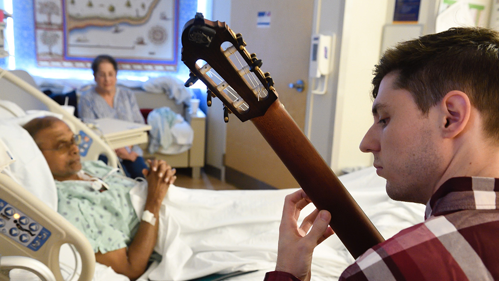 A guitarist plays for a hospital patient