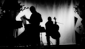 Silhouettes of a musician playing cello and and another looking at sheet music