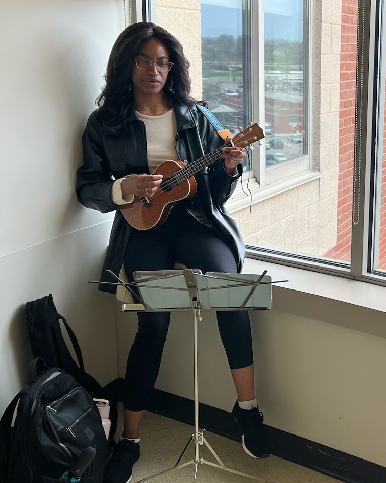 Sound Rounds musician plays the ukulele in a window sill of a hospital